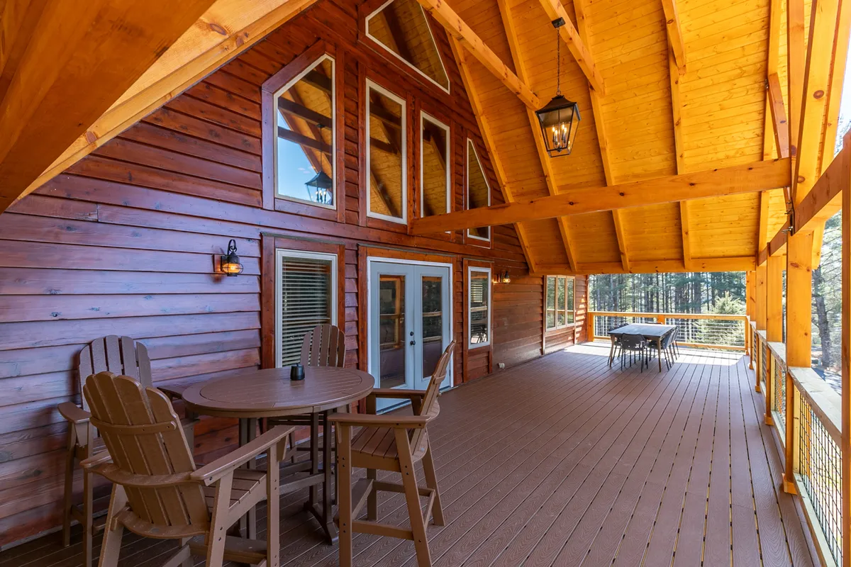 A tranquil deck scene featuring wooden beams, comfortable outdoor furniture, and expansive views. The setup is perfect for relaxing or socializing after a day exploring, with sunset and stargazing opportunities.